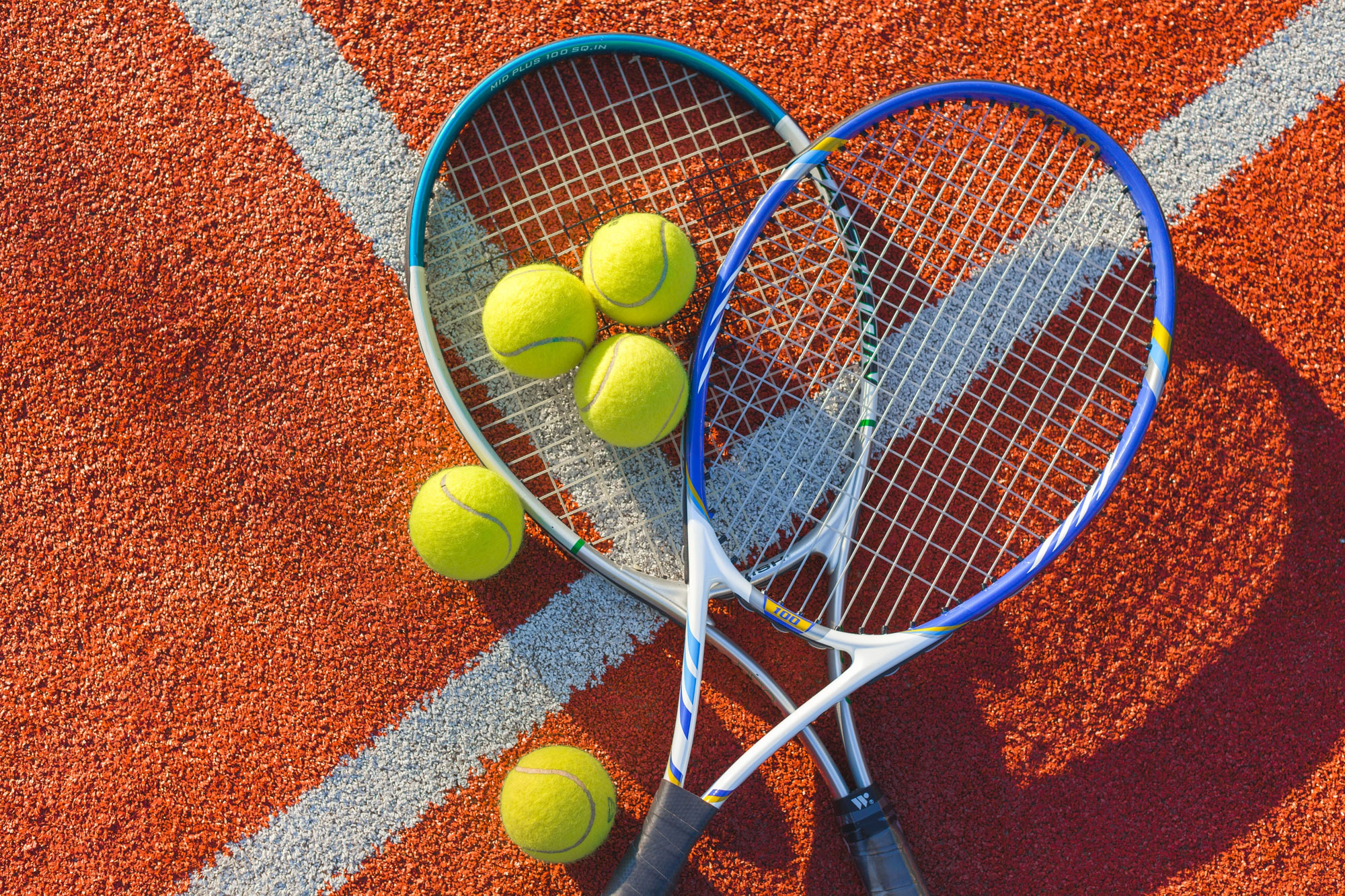 tennis rackets and balls on a clay court